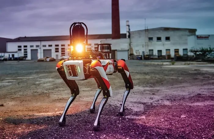 Robot de course Spot au crépuscule sur un site industriel.
