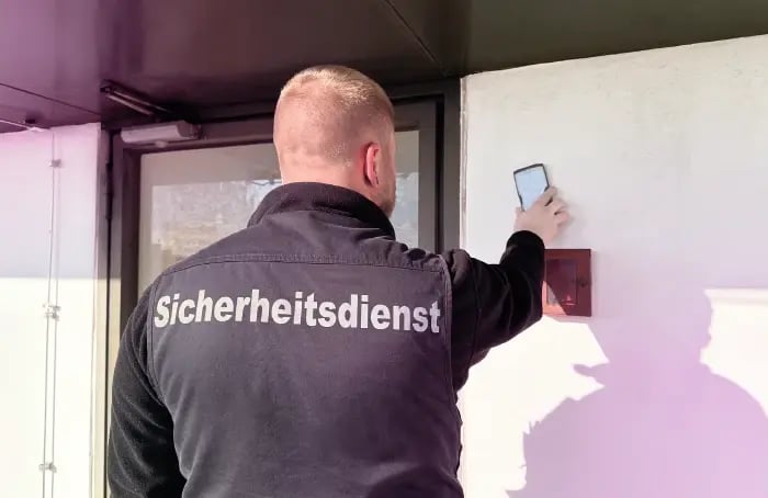Un agent de sécurité d'UMG facilities GmbH scannant un point de contrôle COREDINATE.