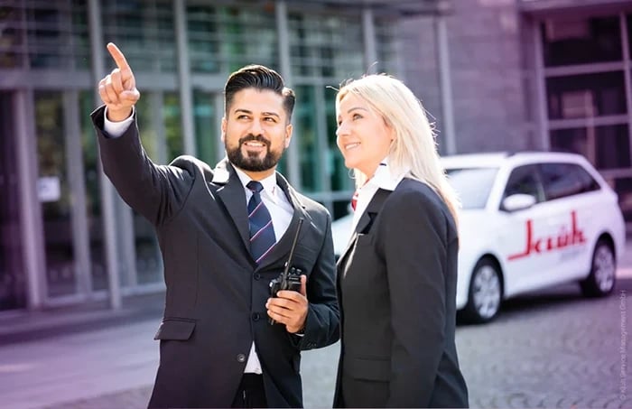 Employé de Klueh Security avec radio devant la voiture de société