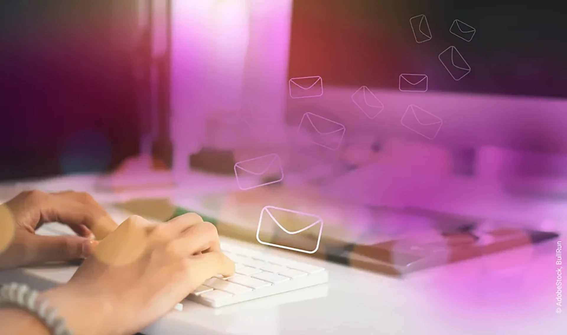 Hands on keyboard in front of a screen and flying letter icons